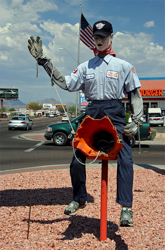 A street side mannequin welcoming drivers to stop by and have their transmission fixed here.