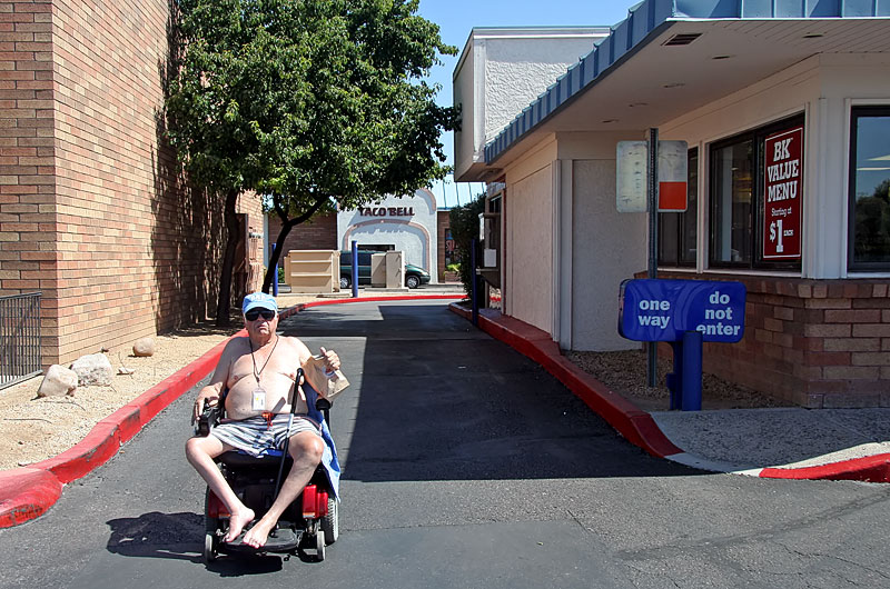 Old man in a wheelchair leaving the drive-thru at a local burger shop in Phoenix, Arizona