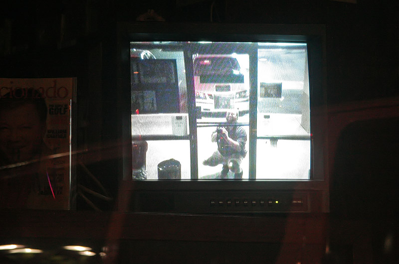 Self portrait via surveillance video shown on a monitor through a business window