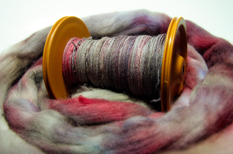 A bobbin of yarn spun from roving dyed by Caroline Wise