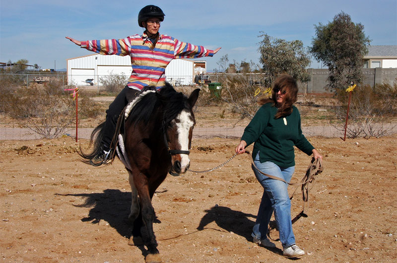 Caroline Wise with Celia Petersen leading Pawnee for a horse riding lesson at Chile Acres in Tonopah, Arizona