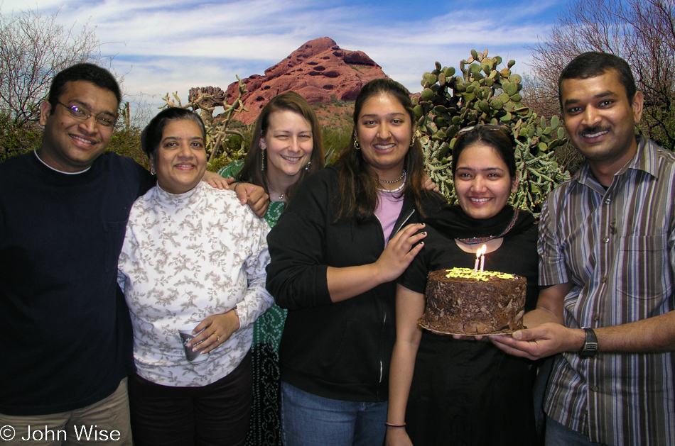 Rinku holding a chocolate cake on her birthday surrounded by friends.