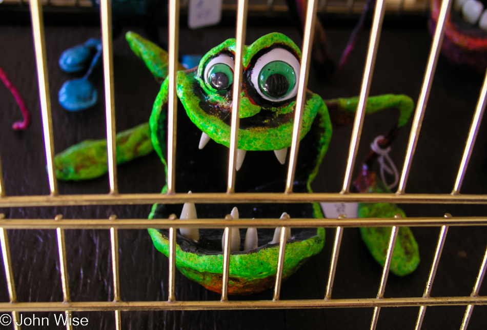 Green bug eyed creature from Bungled Jungle staring out of its cage at the Arizona Renaissance Festival