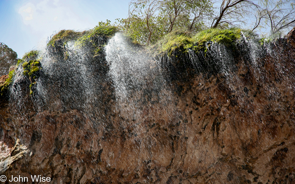 183 feet above the stream bed below a fine mist descends from a small waterfall draping over the Tonto Natural Bridge in Arizona