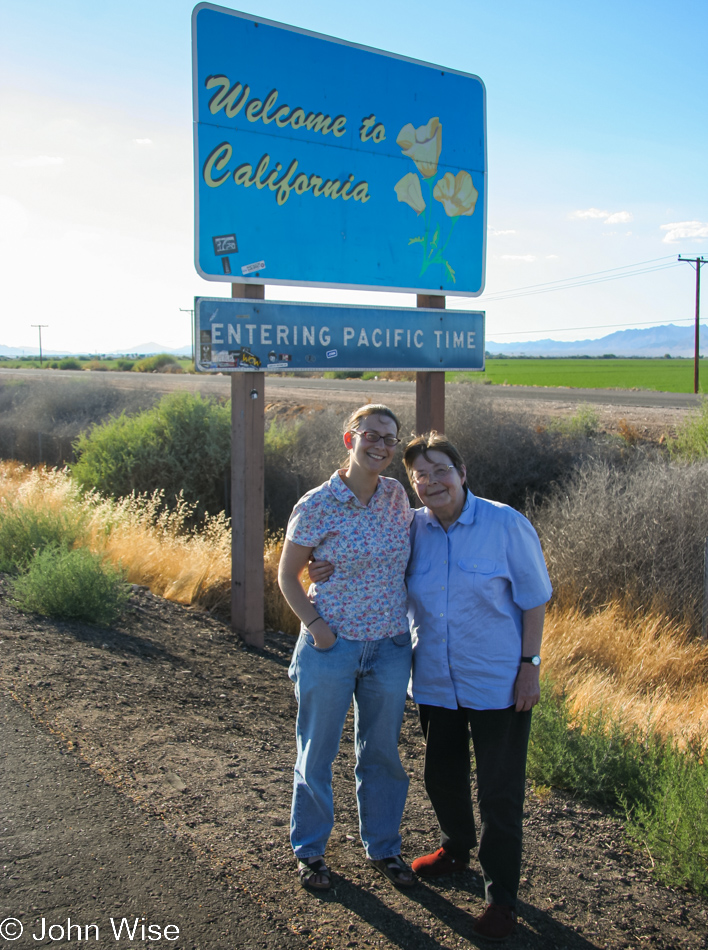 Jutta and Caroline standing in front of the Welcome to California state shield near Blythe and the Arizona border.