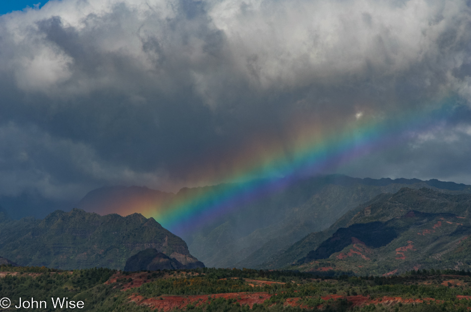 A rainbow glows before Kaanakeakua in the background as we look across the Kekaha Ditch on Kauai, Hawaii