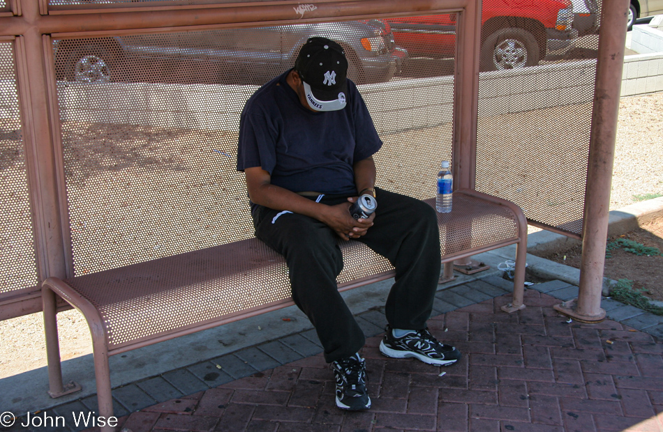 A man asleep and probably drunk at a bus stop in 115-degree weather - Phoenix, Arizona