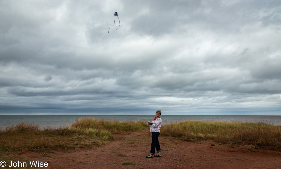 Caroline Wise flying Happy McKiteFace at North Cape Lighthouse on Prince Edward Island, Canada